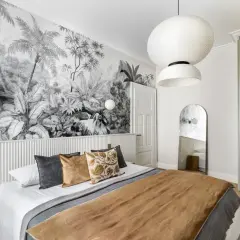 Une chambre avec une tête de lit en papier peint jungle. Le papier peint noir et blanc crée une ambiance tropicale.