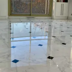 Sol en marbre blanc poli, orné de carreaux noirs, reflétant la lumière. Une rénovation marbre réussie qui illumine la pièce.
