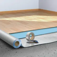 Préparation pour la pose sous couche parquet : rouleau isolant, ruban adhésif et cutter sur un sol brut.