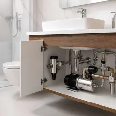 Système de pompe assurant une pression eau maison 4 bars. Tuyauterie chromée sous un lavabo moderne.