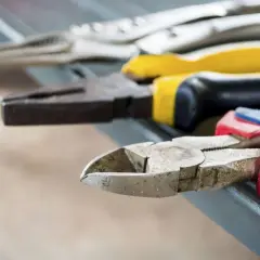 Divers types de pinces bricolage, dont une pince coupante et une pince universelle, sont alignées sur une surface grise.
