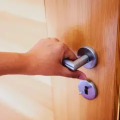 Main tenant essaie de fermer une porte qui ne ferme plus, la poignée est bloquée.