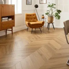 Un salon lumineux avec un parquet point de Hongrie en bois clair. Un fauteuil moutarde et un buffet vintage complètent la décoration.