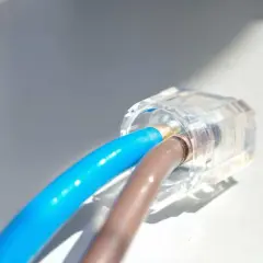 Connexion électrique sécurisée : deux fils, un bleu et un marron, sont raccordés sans domino dans un connecteur transparent.