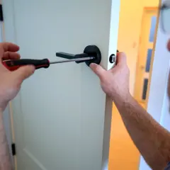 Un homme utilise un tournevis pour changer la poignée de porte.