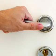 Main tenant essaie d'ouvrir une porte bloquée, sa main agrippe la poignée.