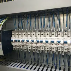 Panneau électrique avec alimentation Allen-Bradley et disjoncteurs. Le code couleur des câbles électriques est visible, indiquant leur section et leur destination.