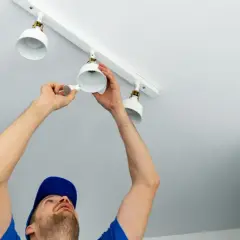 Un électricien installe des spots sur un rail. Il est important de savoir combien de spot par disjoncteur pour une installation sûre.