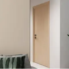 Une porte en bois clair, d'une largeur standard, s'ouvre sur un couloir. Des coussins décoratifs sont posés sur un canapé à gauche.