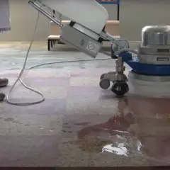 Une machine professionnelle est utilisée pour poncer le carrelage, laissant une surface propre et brillante.