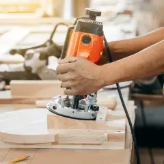 Un artisan utilise une défonceuse pour façonner une pièce de bois.