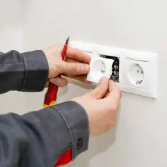 Un électricien installe une prise, prêt à condamner une prise électrique défectueuse.