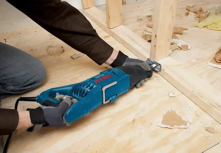 Une scie sabre sert à découper le bois et le métal, comme le montre cette personne qui l'utilise pour démolir une structure.