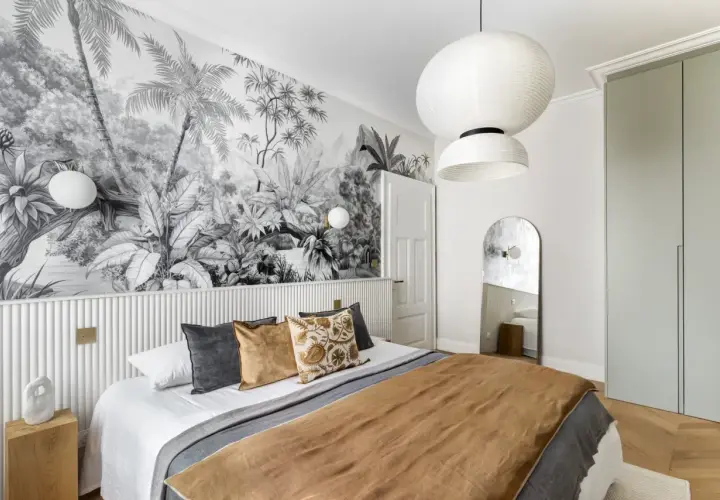Une chambre avec une tête de lit en papier peint jungle. Le papier peint noir et blanc crée une ambiance tropicale.