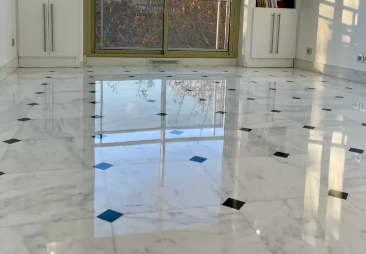 Sol en marbre blanc poli, orné de carreaux noirs, reflétant la lumière. Une rénovation marbre réussie qui illumine la pièce.