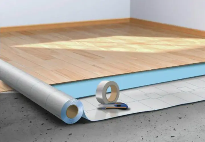 Préparation pour la pose sous couche parquet : rouleau isolant, ruban adhésif et cutter sur un sol brut.