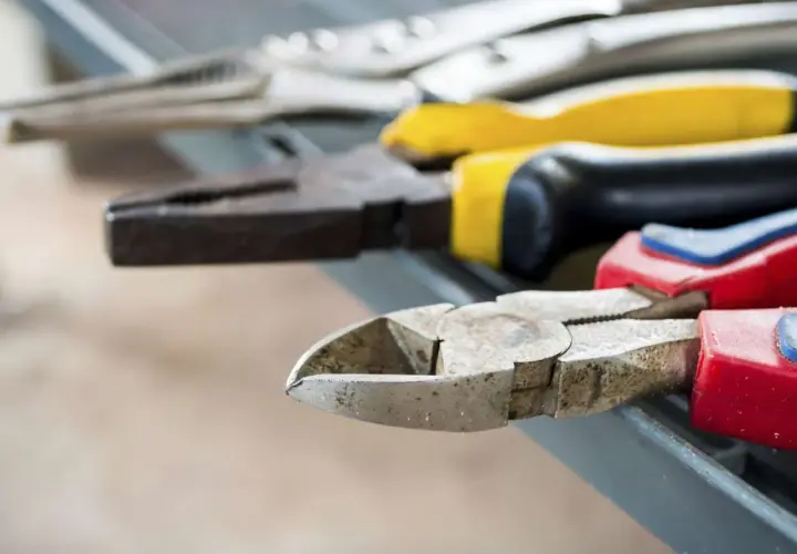 Divers types de pinces bricolage, dont une pince coupante et une pince universelle, sont alignées sur une surface grise.