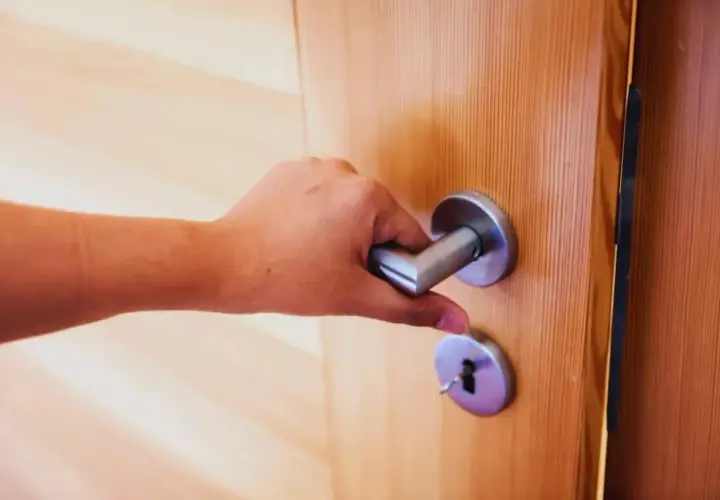 Main tenant essaie de fermer une porte qui ne ferme plus, la poignée est bloquée.