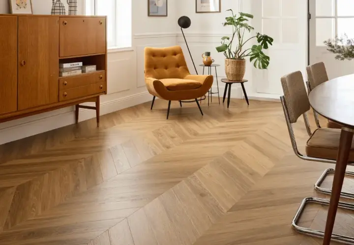 Un salon lumineux avec un parquet point de Hongrie en bois clair. Un fauteuil moutarde et un buffet vintage complètent la décoration.