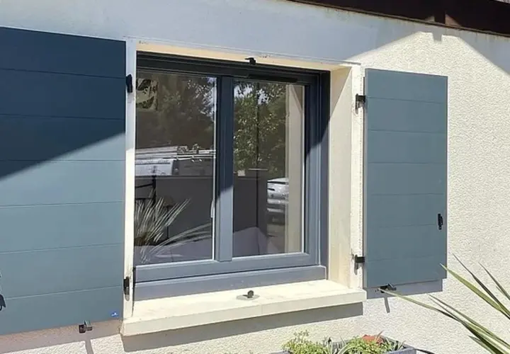 Fenêtre avec volets battants gris anthracite installés, offrant une touche moderne et sécurisée à la façade.