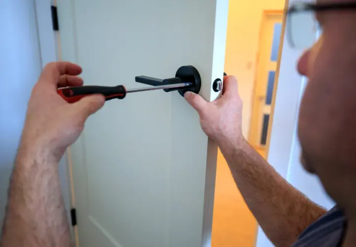 Un homme utilise un tournevis pour changer la poignée de porte.