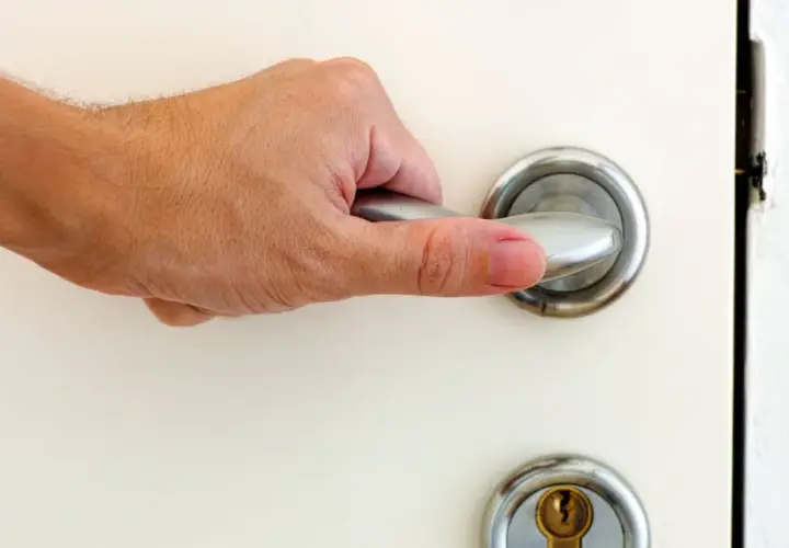 Main tenant essaie d'ouvrir une porte bloquée, sa main agrippe la poignée.