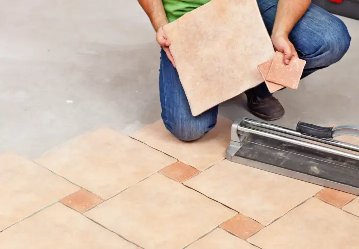 Un carreleur prépare la découpe de carrelage pour un nouveau sol. L'outil de coupe est prêt.