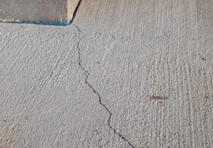 Une fissure traverse une dalle béton fraîchement coulée, témoignant des défis pour faire une dalle béton parfaite.