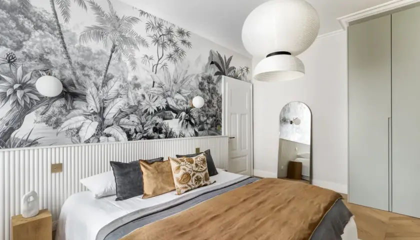 Une chambre avec une tête de lit en papier peint jungle. Le papier peint noir et blanc crée une ambiance tropicale.