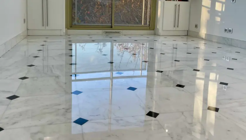Sol en marbre blanc poli, orné de carreaux noirs, reflétant la lumière. Une rénovation marbre réussie qui illumine la pièce.