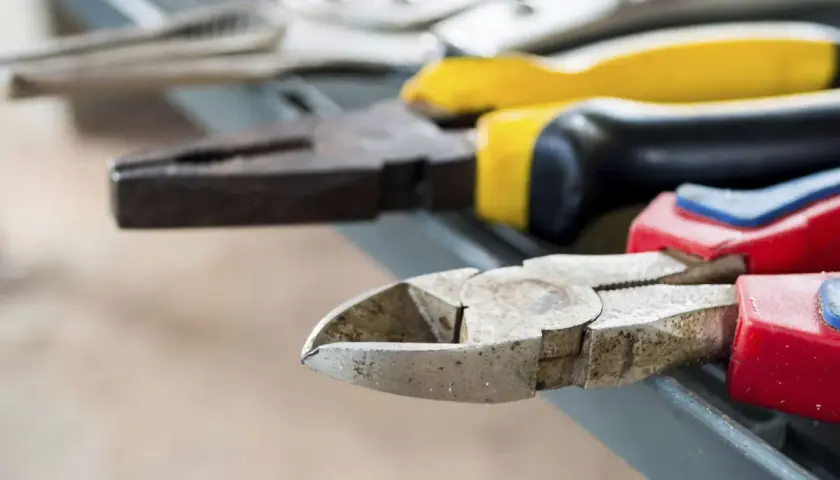 Divers types de pinces bricolage, dont une pince coupante et une pince universelle, sont alignées sur une surface grise.