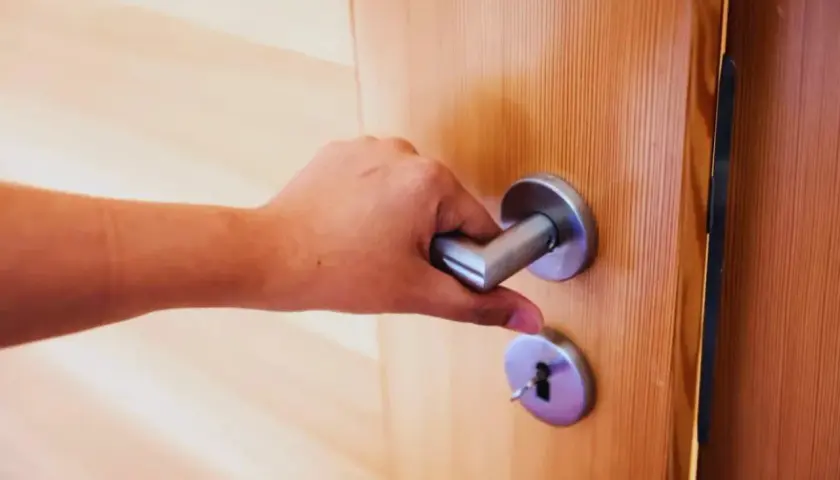 Main tenant essaie de fermer une porte qui ne ferme plus, la poignée est bloquée.
