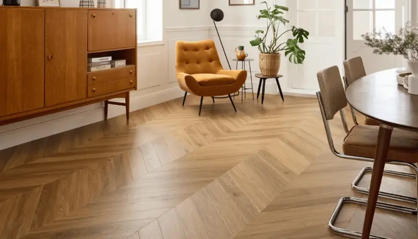Un salon lumineux avec un parquet point de Hongrie en bois clair. Un fauteuil moutarde et un buffet vintage complètent la décoration.