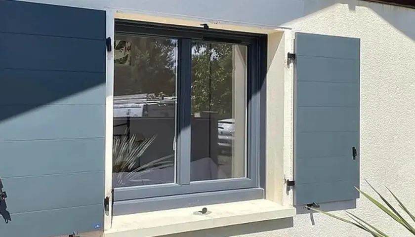Fenêtre avec volets battants gris anthracite installés, offrant une touche moderne et sécurisée à la façade.