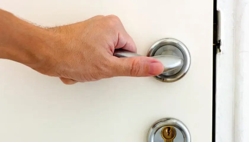 Main tenant essaie d'ouvrir une porte bloquée, sa main agrippe la poignée.
