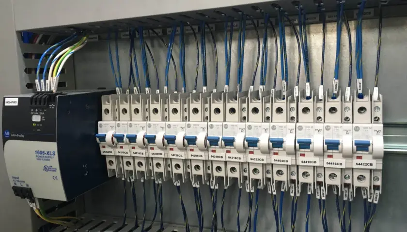 Panneau électrique avec alimentation Allen-Bradley et disjoncteurs. Le code couleur des câbles électriques est visible, indiquant leur section et leur destination.