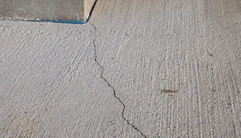 Une fissure traverse une dalle béton fraîchement coulée, témoignant des défis pour faire une dalle béton parfaite.
