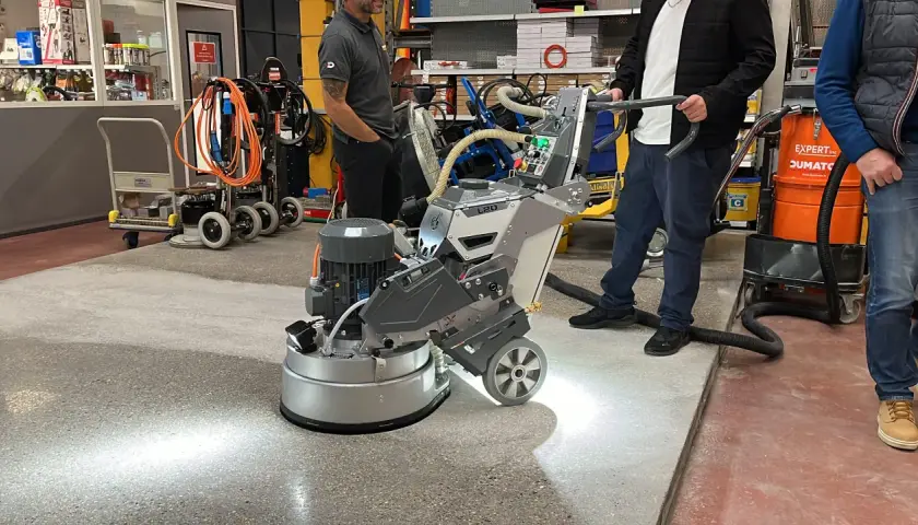 Une machine professionnelle est utilisée pour poncer du béton, créant une surface lisse et propre.