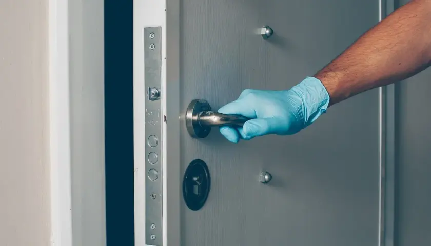 Main tenant, ganté, ouvre une porte voilée.
