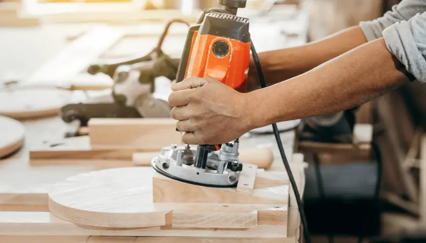 Un artisan utilise une défonceuse pour façonner une pièce de bois.