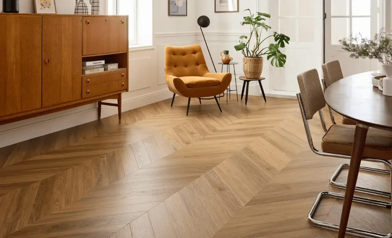 Un salon lumineux avec un parquet point de Hongrie en bois clair. Un fauteuil moutarde et un buffet vintage complètent la décoration.