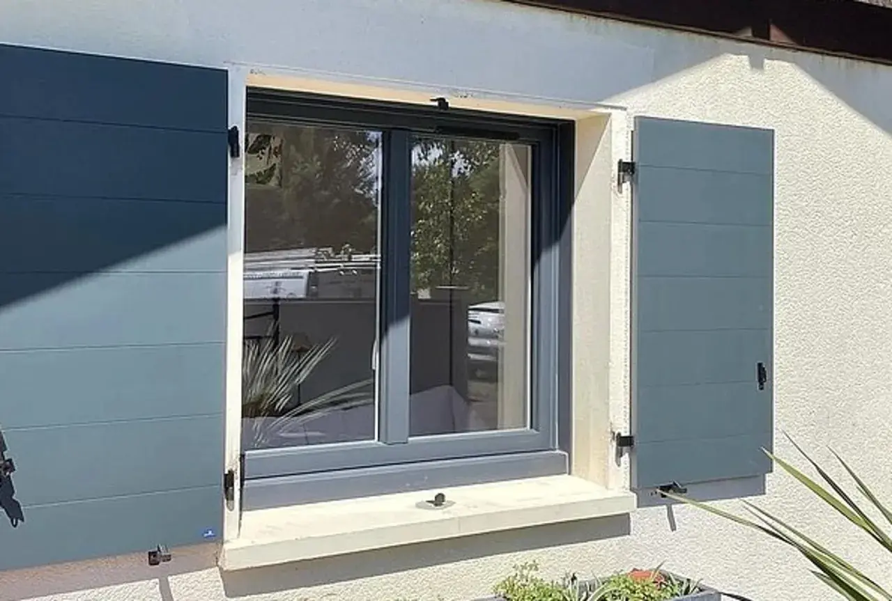 Fenêtre avec volets battants gris anthracite installés, offrant une touche moderne et sécurisée à la façade.