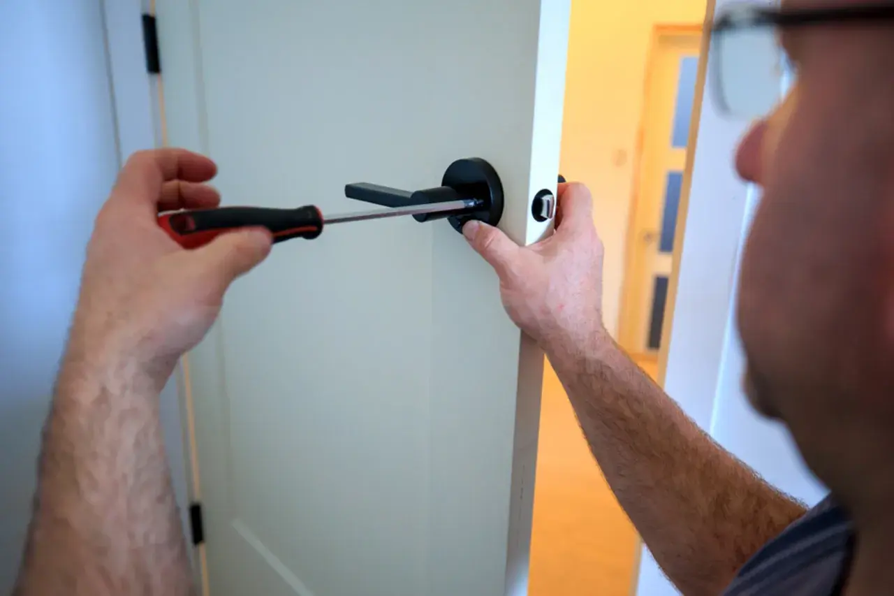 Un homme utilise un tournevis pour changer la poignée de porte.
