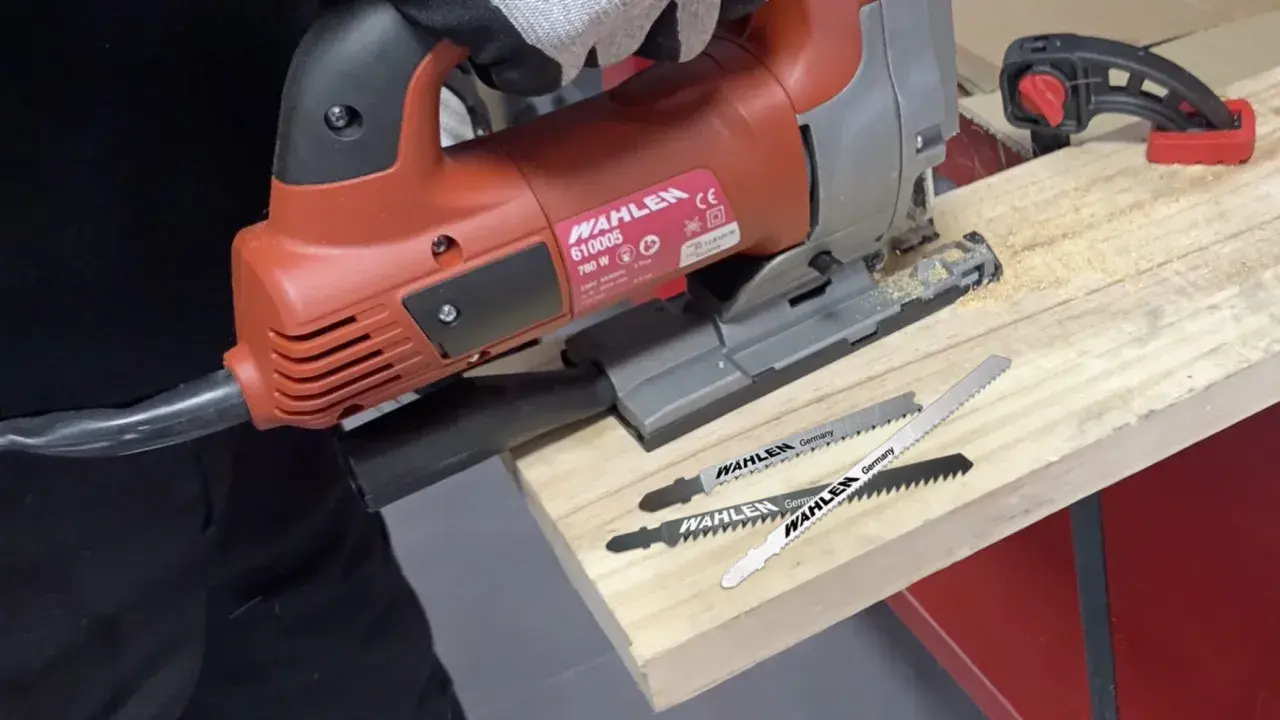 Un bricoleur utilise une scie sauteuse, un type de scie, pour travailler du bois. Trois lames de scie sont visibles.