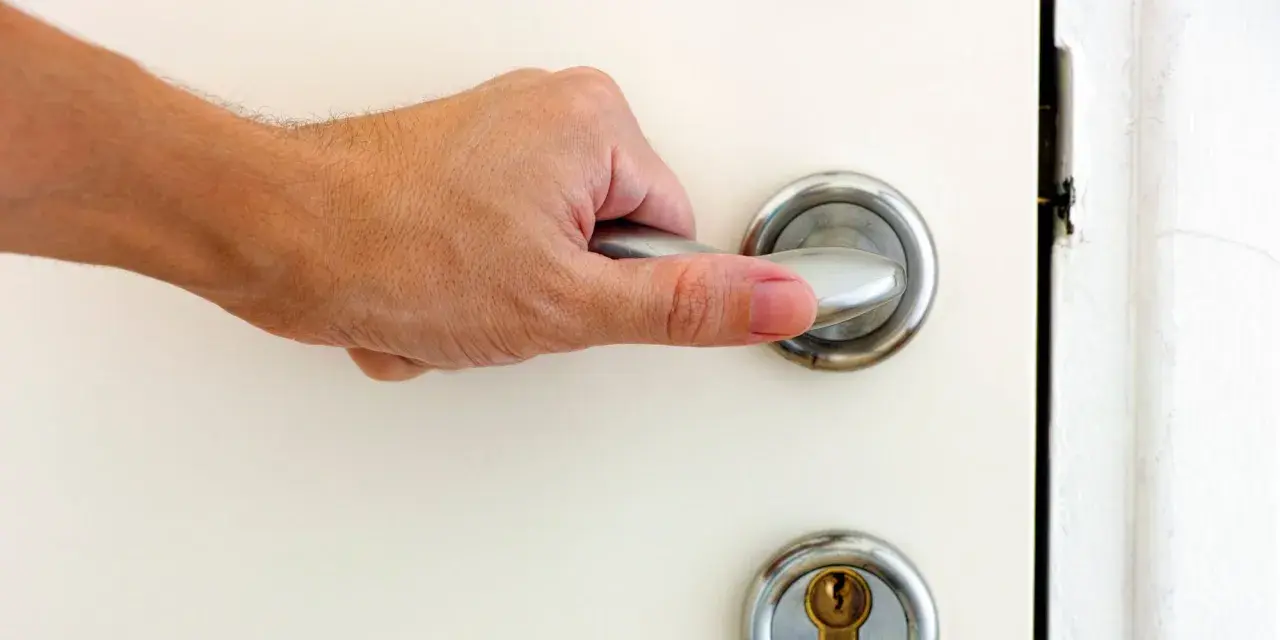 Main tenant essaie d'ouvrir une porte bloquée, sa main agrippe la poignée.
