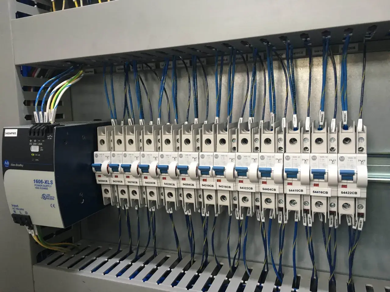 Panneau électrique avec alimentation Allen-Bradley et disjoncteurs. Le code couleur des câbles électriques est visible, indiquant leur section et leur destination.