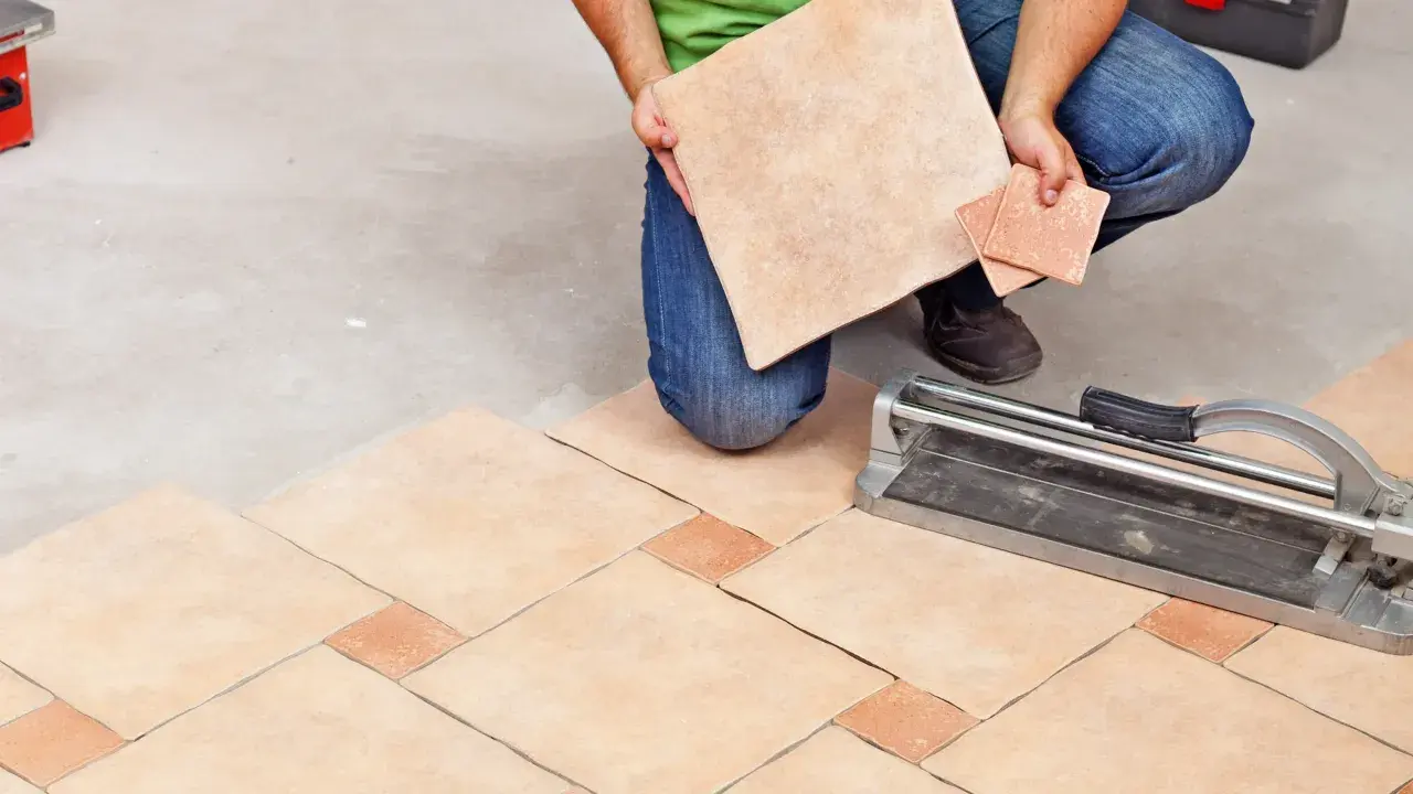 Un carreleur prépare la découpe de carrelage pour un nouveau sol. L'outil de coupe est prêt.