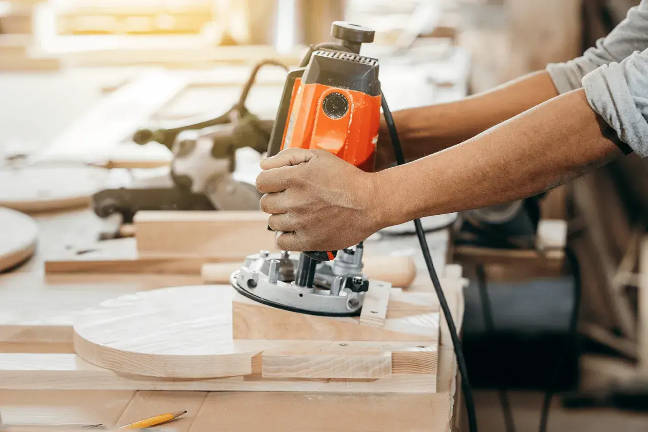 Un artisan utilise une défonceuse pour façonner une pièce de bois.