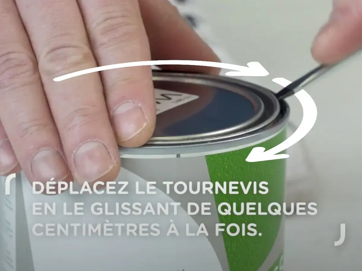 Comment ouvrir un pot de peinture : une main utilise un tournevis pour soulever le couvercle, suivant les flèches indicatrices.