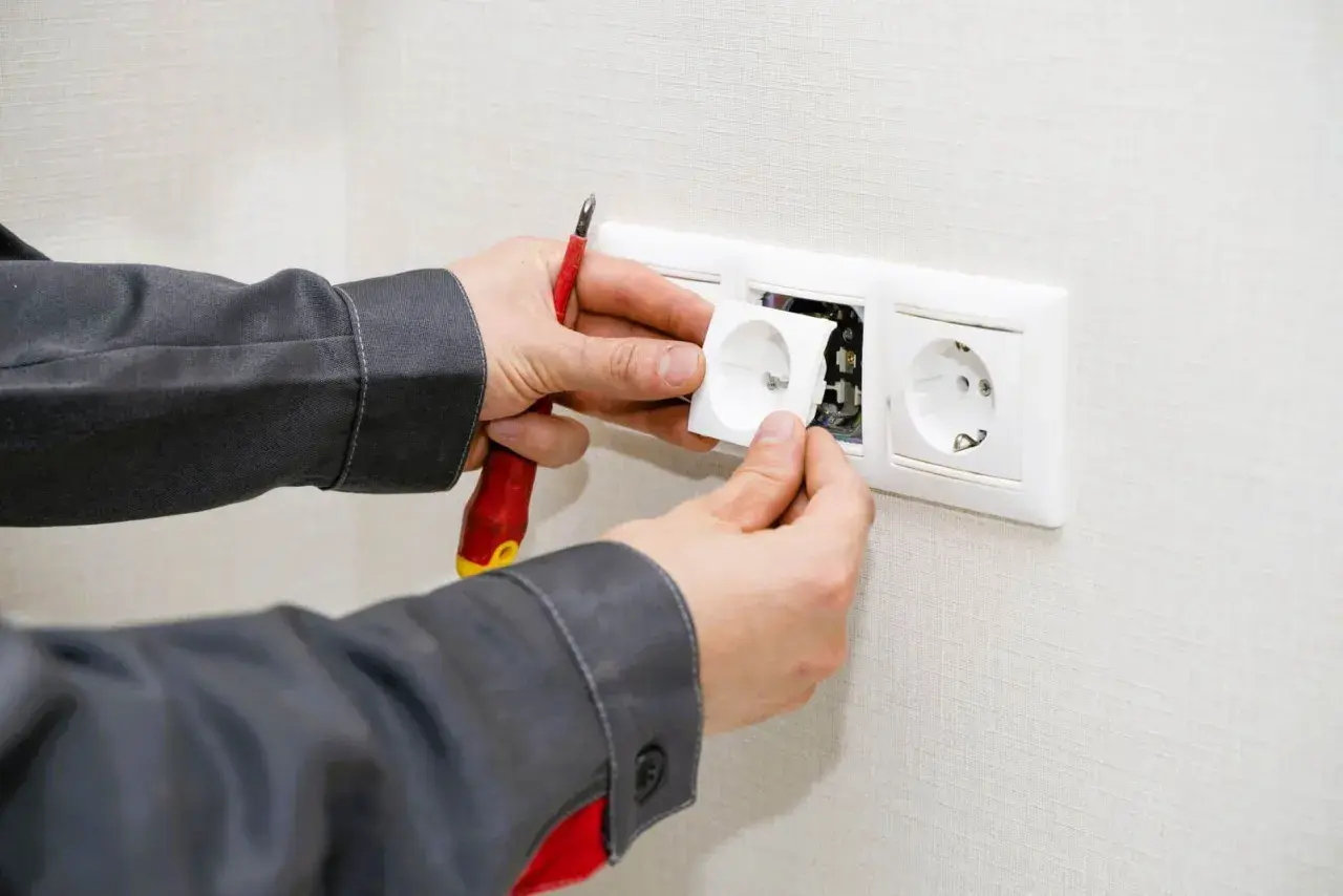 Un électricien installe une prise, prêt à condamner une prise électrique défectueuse.
